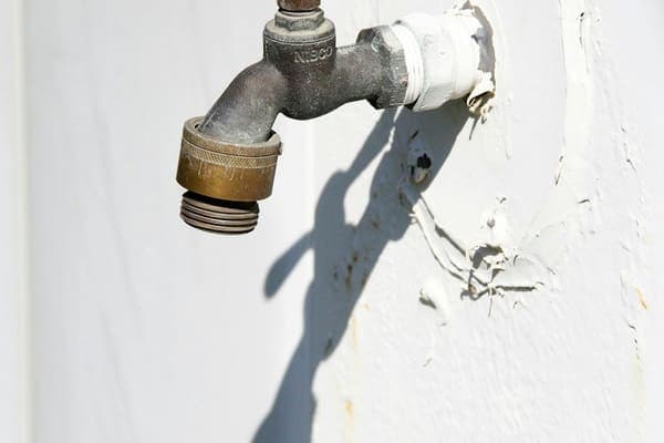 Robinet en laiton fixé sur un mur blanc