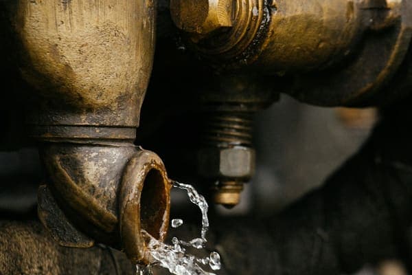 Raccord en laiton d'où s'écoule un filet d'eau